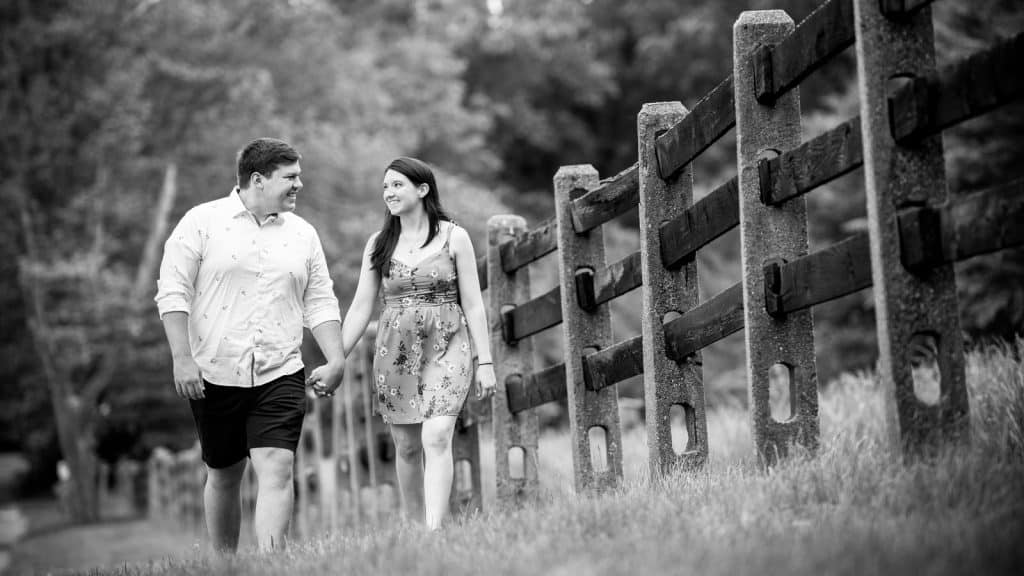 engagement session walking near a wooden fence
