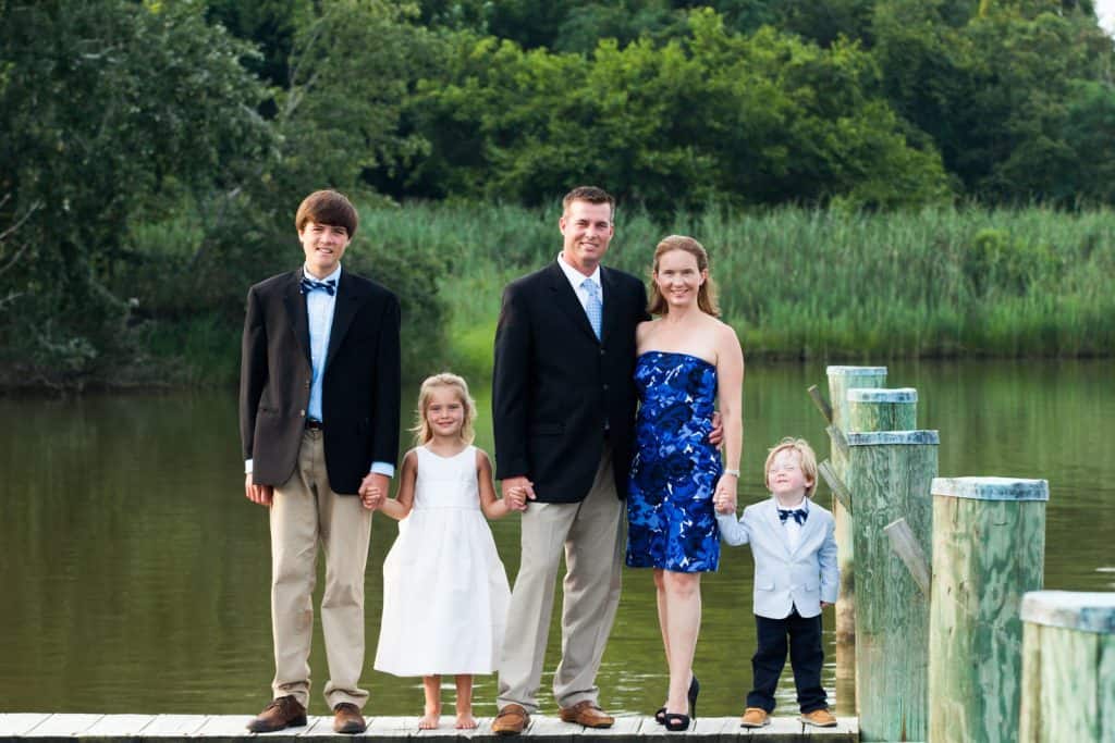 family standing on a dock holding hands