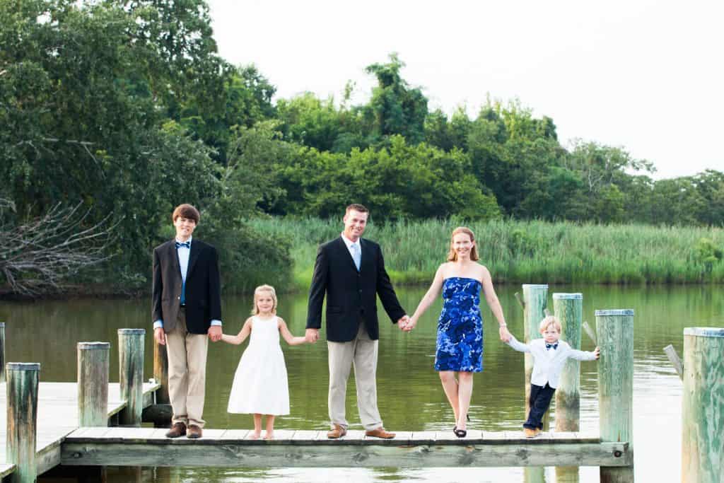 family standing on a dock holding hands