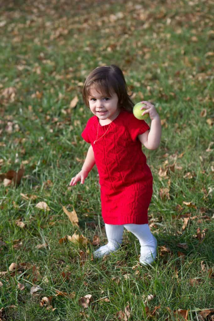 young girl in red dress holding a tennis ball