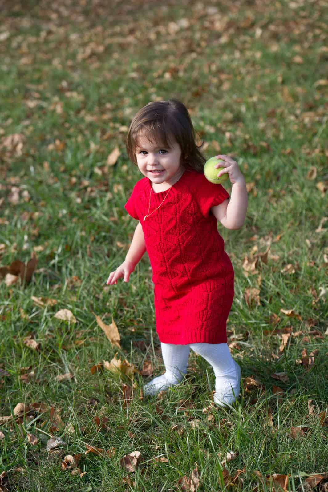 young girl in red dress holding a tennis ball