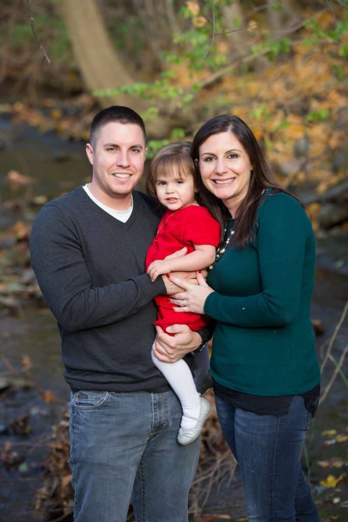 father and mother with daughter in front of stream