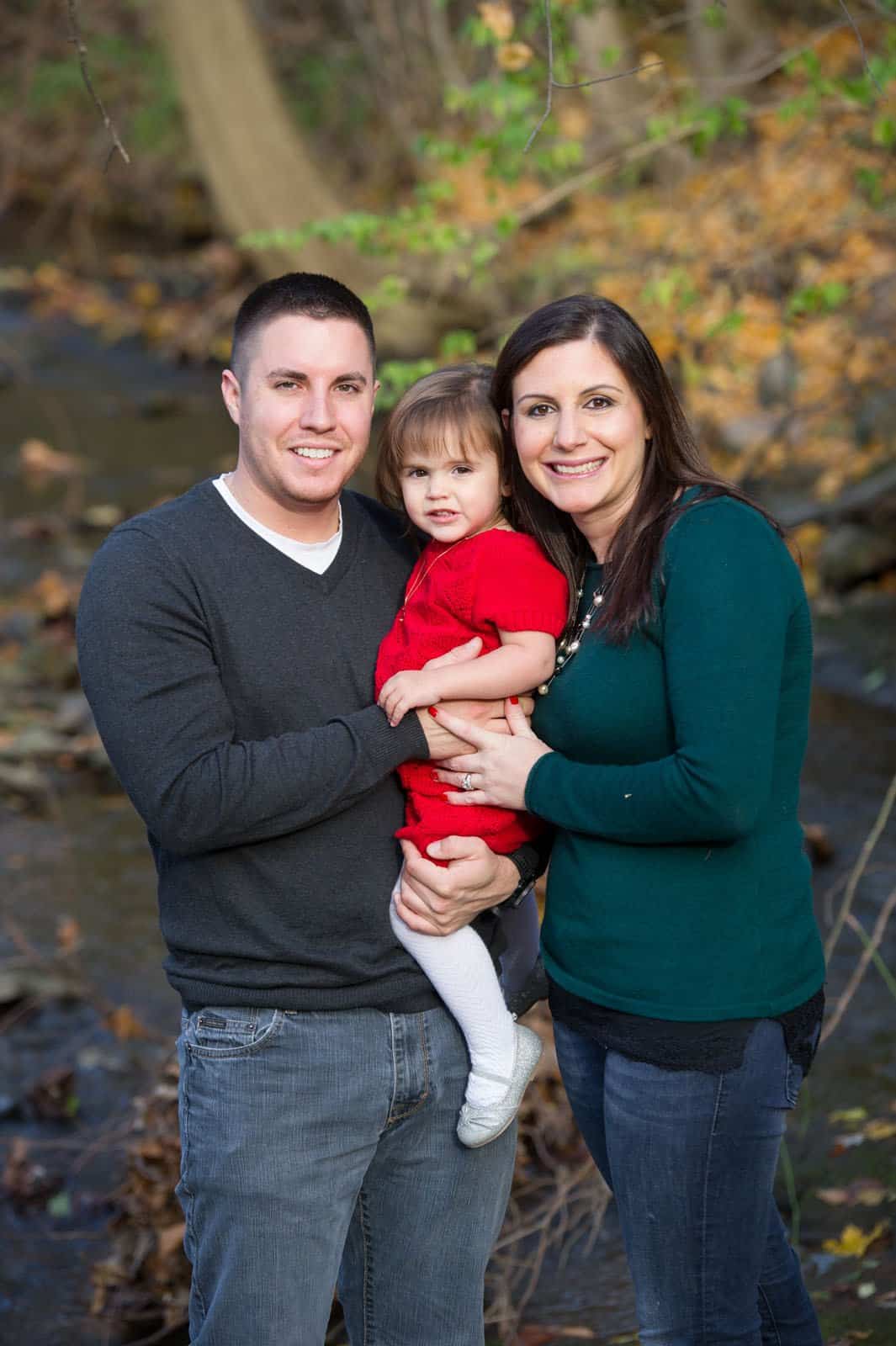 father and mother with daughter in front of stream