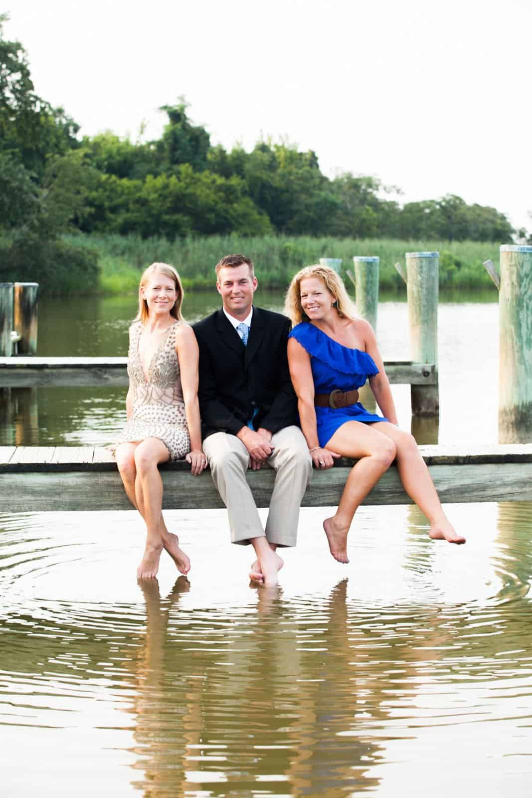 brother and sisters sitting on a dock with bare feet